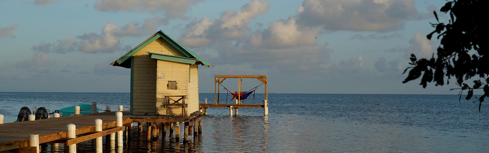 A hut sits at the end of the dock and the sun is setting behind the camera.